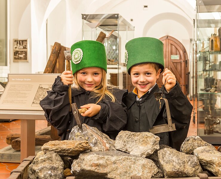 zwei Kinder in Bergbauuniform, an einem Erzhunt in der Bergbauausstellung des Stadt- und Bergbaumuseums Freiberg stehend (Rene Jungnickel)