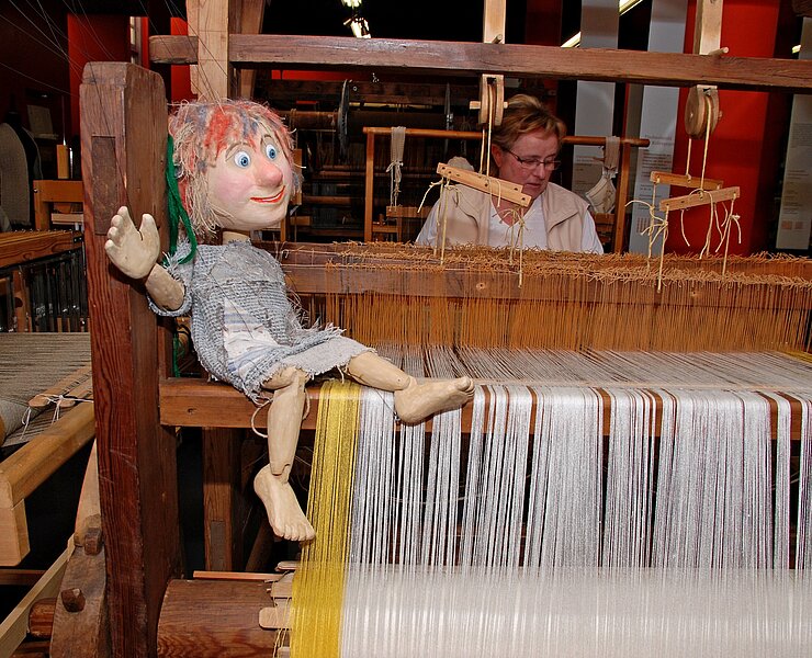 Museumsmaskottchen "Wuschel" auf Webstuhl (Sonja Reupert, Stadt Oederan)